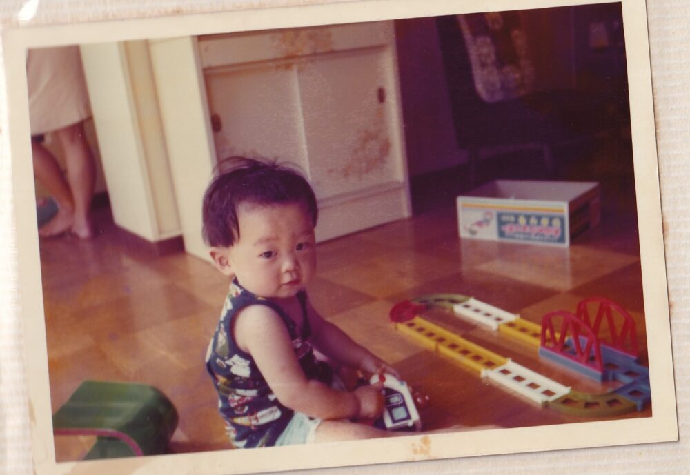 床にプラレールを並べて遊ぶ1歳のころの鈴木先生